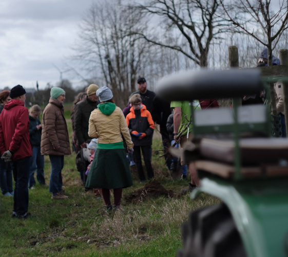 KI generiert: Eine Gruppe von Menschen auf einem Feld, nah bei einem Traktor.