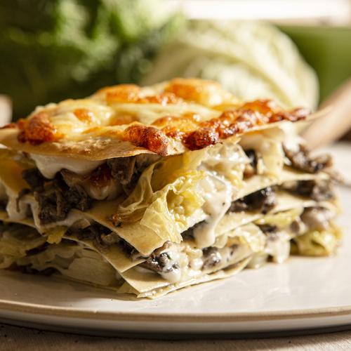 KI generiert: Ein Stück Lasagne mit goldener Käsekruste auf einem Teller.