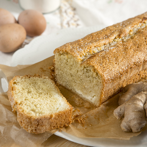 KI generiert: Ein angeschnittener Kuchen auf Backpapier mit Eiern und Ingwer im Hintergrund.