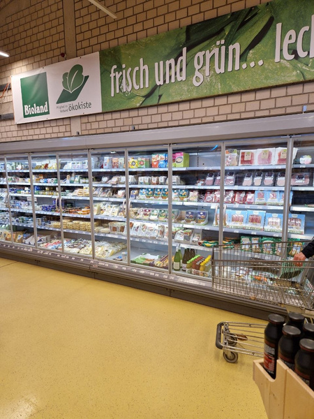 KI generiert: Der Hauptinhalt des Bildes ist ein Kühlregal einer Ökokiste mit dem Slogan "frisch und grün...led".