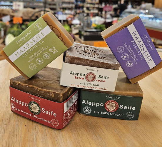 KI generiert: Seifenstapel in einem Geschäft, einschließlich Haarseife Citronella und Aleppo Seife aus Olivenöl.