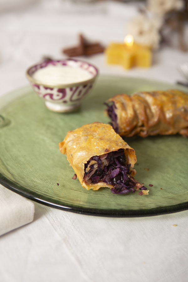 KI generiert: Ein Teller mit Strudel, gefüllt mit Rotkohl, und ein Schälchen Sauce.