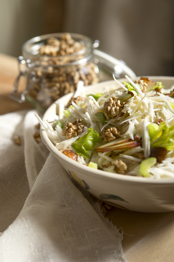 KI generiert: Ein frischer Salat mit Nüssen in einer Schüssel; im Hintergrund ein Glas mit Nüssen.