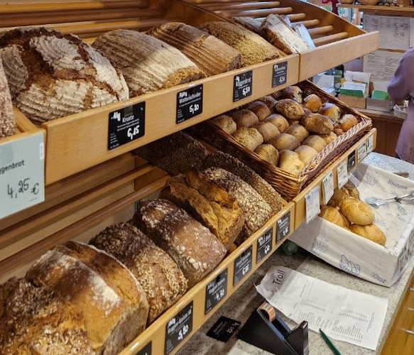 KI generiert: Eine Bäckereitheke mit verschiedenen Broten. Preisschilder sind sichtbar: "Kruste 6,45 €", "Vollkornbrot 4,95 €".