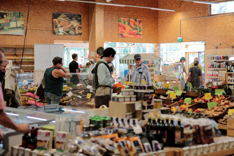 KI generiert: Ein Bioladen mit mehreren Kunden und verschiedenen Obst- und Gemüsesorten.